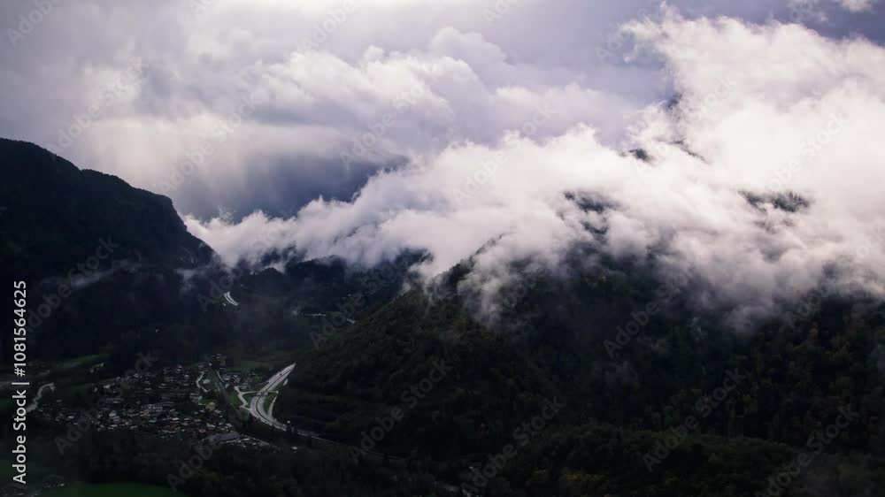 The drone flies through the clouds, revealing a valley, surrounded by mountains, with landscapes, roads, village The drone flies through the clouds, revealing a valley, surrounded by mountains, with landscapes, roads, village