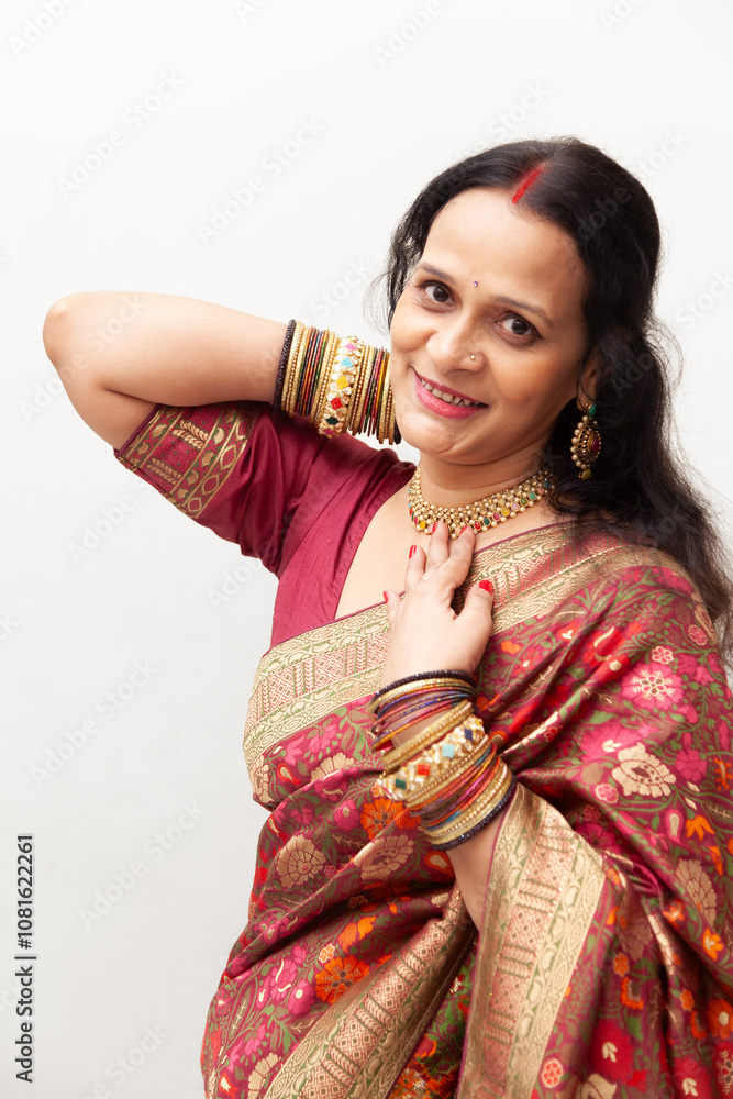A joyful Indian woman from India, dressed in a traditional saree, is adjusting her necklace. A joyful Indian woman from India, dressed in a traditional saree, is adjusting her necklace.