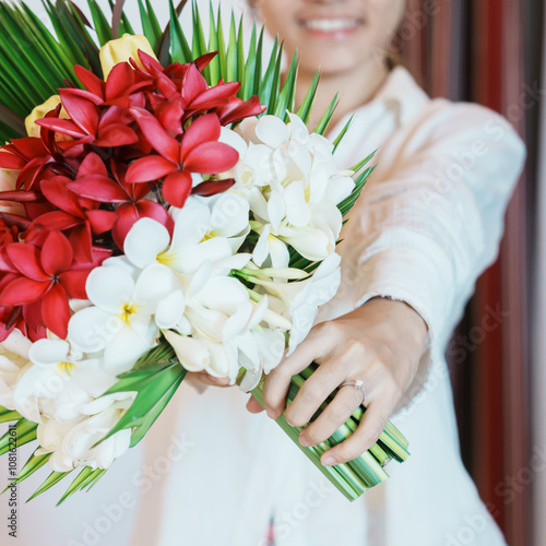 Woman hand wearing a diamond ring and holding flower bouquet. Idea for marriage proposal, romantic surprise, wedding, engagement and valentines day concept