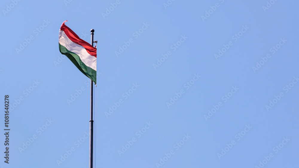 Hungarian flag gently fluttering against bright blue sky Hungarian flag gently fluttering against bright blue sky