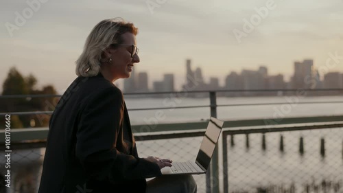 Professional confidently works on laptop against stunning city skyline backdrop