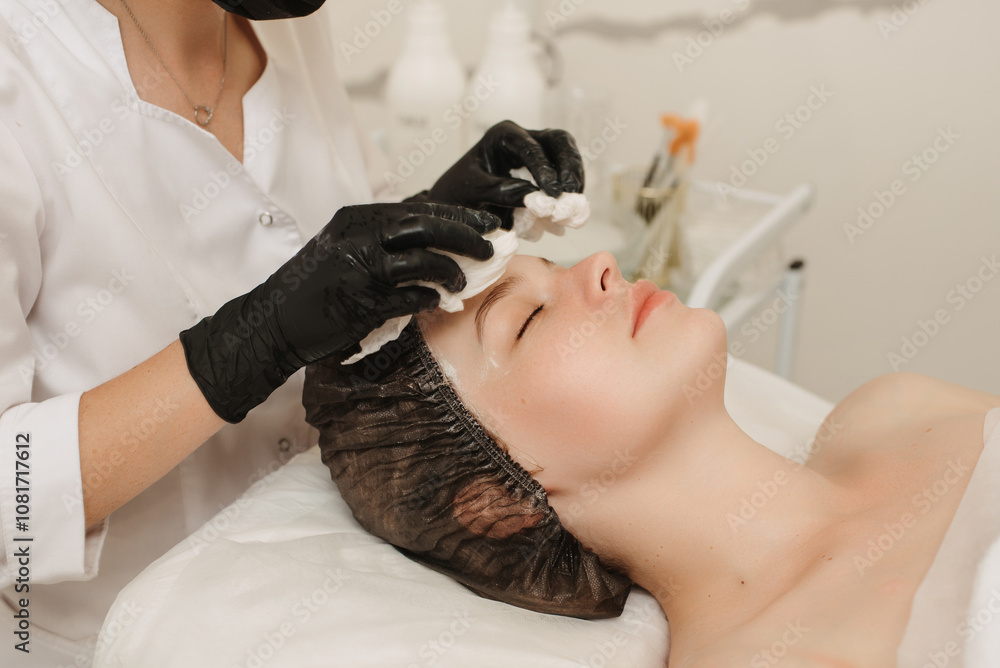 The cosmetologist cleanses the client's skin with cotton pads. The cosmetologist cleanses the client's skin with cotton pads.