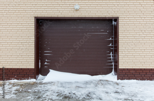 A garage door is open and snow is piled up against it photo