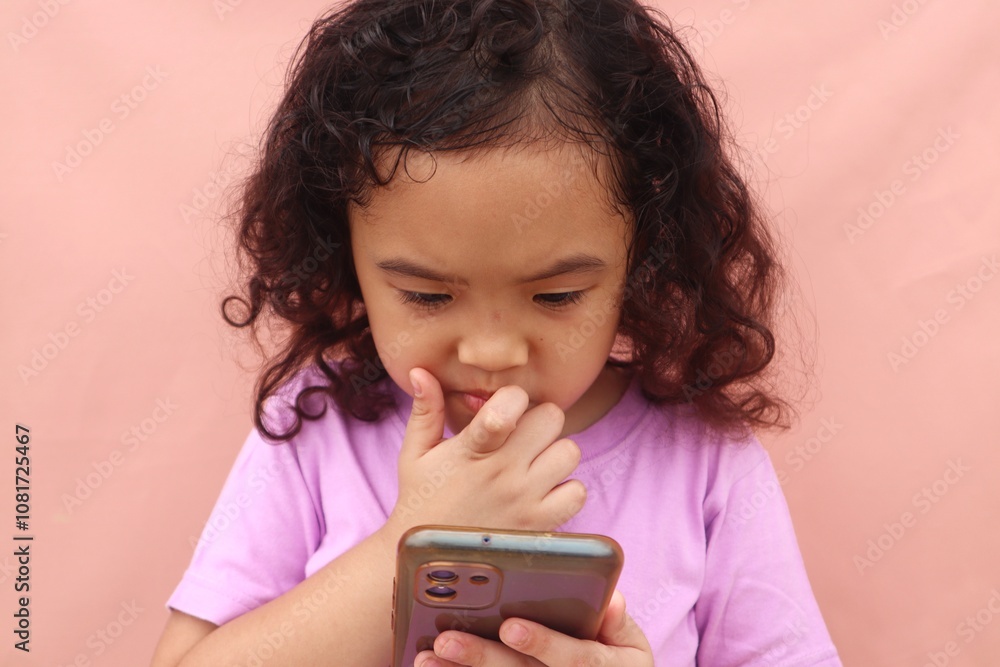 Asian girl child is seriously using cell phone with adorable face, close up view. Asian girl child is seriously using cell phone with adorable face, close up view.