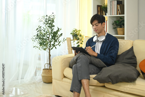 Creative freelancer with headphone working with digital tablet in living room