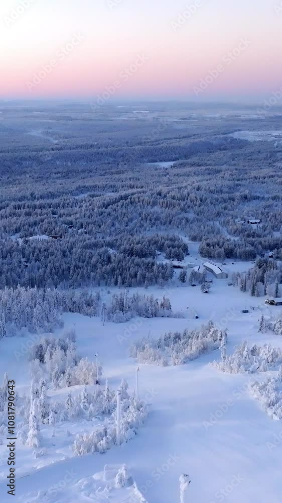 Vertical drone shot over the slopes of Sallatunturi, winter sunrise in Finland Vertical drone shot over the slopes of Sallatunturi, winter sunrise in Finland