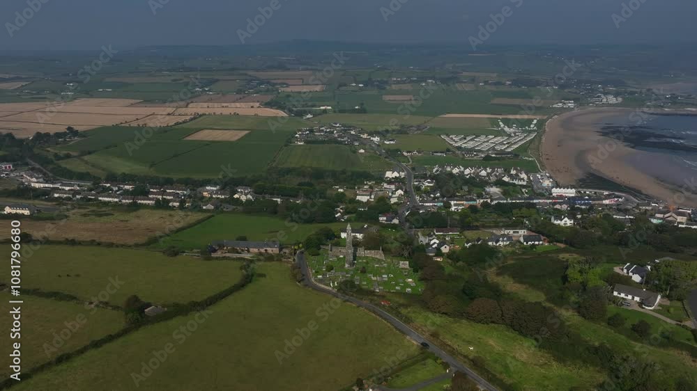 St. Declan's Monastery, Ardmore, County Waterford, Ireland, September 2024. Drone panoramic high angle orbit clockwise around Round Tower with farmland, beach and ocean waves crashing on the coast. St. Declan's Monastery, Ardmore, County Waterford, Ireland, September 2024. Drone panoramic high angle orbit clockwise around Round Tower with farmland, beach and ocean waves crashing on the coast.