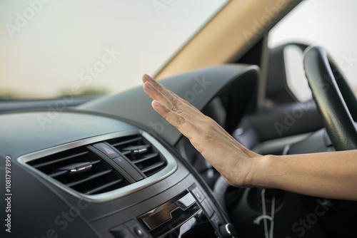 Car air conditioning, woman's hand is checking the air flow of the car's air conditioning cooling system. Close-up of a hand on the air vent of a car's air conditioning system.