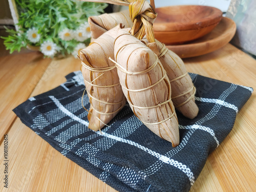 Lepet is a cake made from glutinous rice filled with banana or grated coconut or red bean, then wrapped in young coconut leaves and steamed until cooked photo