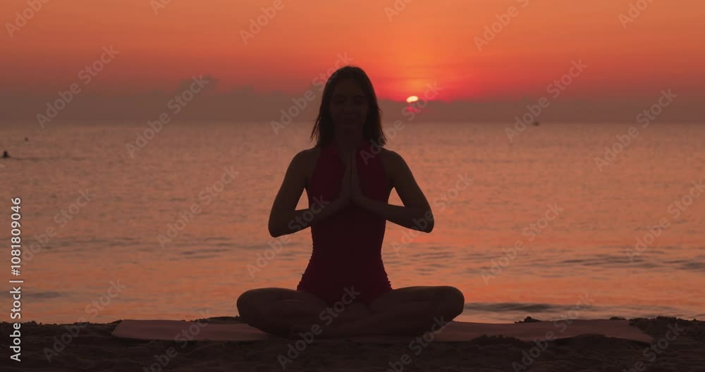 A serene silhouette of a woman practicing lotus pose with hands in prayer mudra on the beach during sunrise. This peaceful image is ideal for promoting mindfulness, wellness, and yoga, capturing the A serene silhouette of a woman practicing lotus pose with hands in prayer mudra on the beach during sunrise. This peaceful image is ideal for promoting mindfulness, wellness, and yoga, capturing the