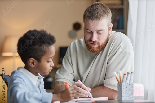 Schilderij op canvas Medium shot of supportive dad helping little adopted son with homework while sit