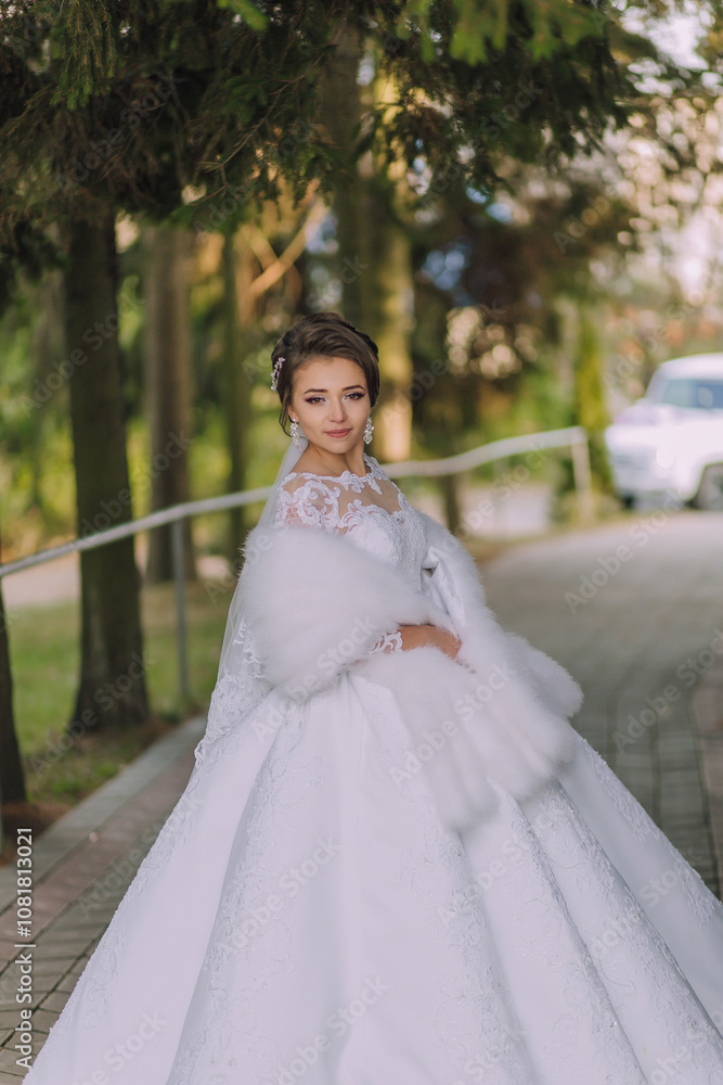 A woman in a white dress is posing for a picture. She is wearing a fur coat and has her hair in a bun. The background features a car and a tree A woman in a white dress is posing for a picture. She is wearing a fur coat and has her hair in a bun. The background features a car and a tree