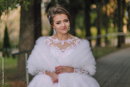 A woman in a white dress is wearing a fur stole. She is smiling and looking at the camera photo