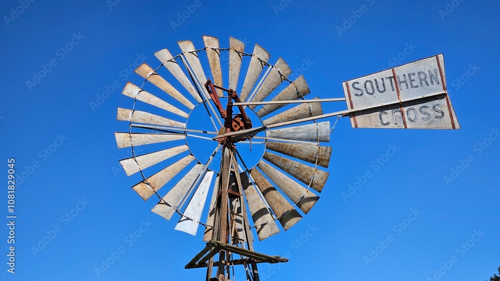 Australian steel windmill against a clear blue sky. Shiny metal blades reflecting the sun. Australian steel windmill against a clear blue sky. Shiny metal blades reflecting the sun.