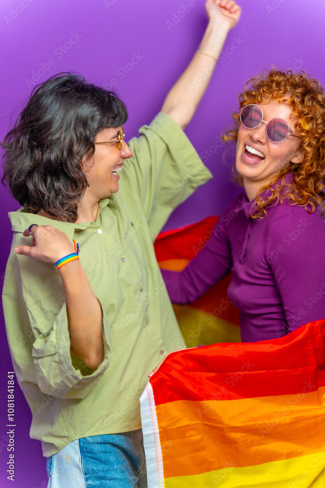 Obraz premium Happy lesbian couple dancing wrapped with lgbt rainbow flag