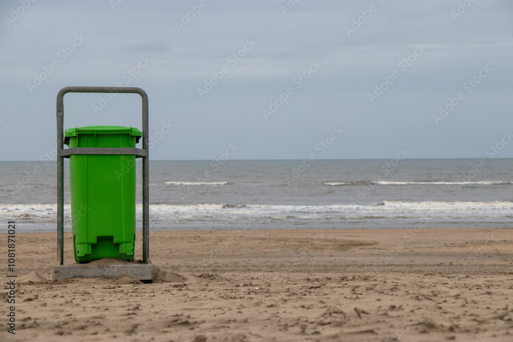 Green Trash Bin on Sandy Beach Facing the Ocean: Simple Coastal Scene Emphasizing Cleanliness and Environmental Care Green Trash Bin on Sandy Beach Facing the Ocean: Simple Coastal Scene Emphasizing Cleanliness and Environmental Care