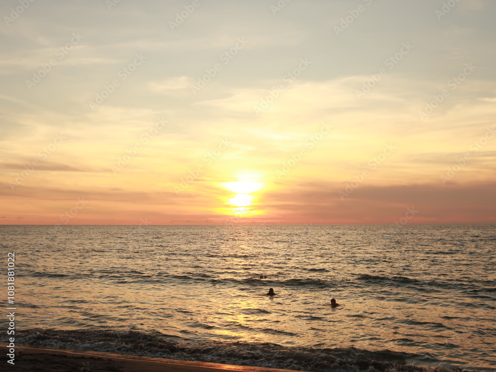 Obraz premium Tranquil Sunset Over the Ocean with Swimmers