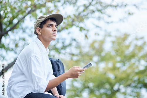 スマートフォンを持ってくつろぐインド人留学生の男性