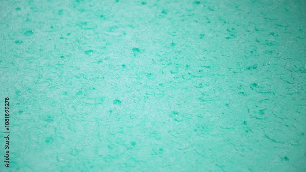 Slow motion top-down shot of rain drops hitting pool surface, creating turbulent surface and ripples Slow motion top-down shot of rain drops hitting pool surface, creating turbulent surface and ripples
