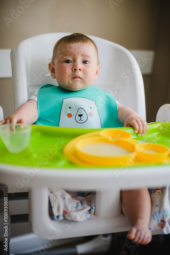 Portrait of a small child at a table. Eating porridge, lunch