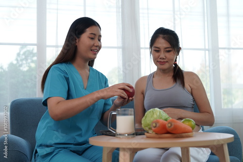 Asian nurse nutritionist holding tablet recommends fruit and milk food to pregnant Asian mothers. Food is nutritious for the baby in the womb.

 photo