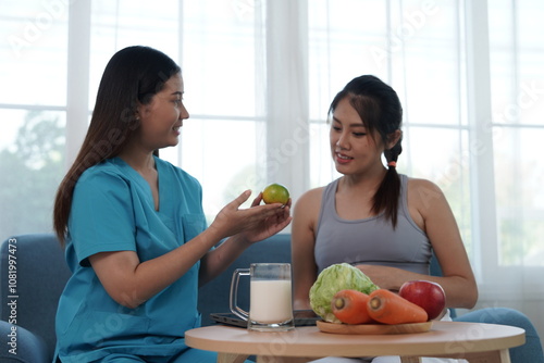 Obraz na płótnie Asian nurse nutritionist holding tablet recommends fruit and milk food to pregnant Asian mothers. Food is nutritious for the baby in the womb.
w salonie
