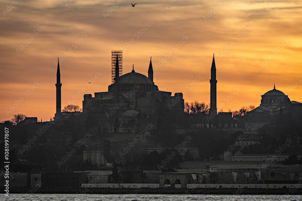 Fototapeta premium Beautiful sunset at Bosphorus mosque minaret silhouette, boats on the water Sultanahmet area of Istanbul Turkey