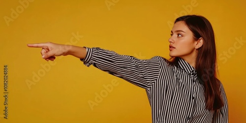 A woman wearing a striped shirt points at something, possibly an object or direction