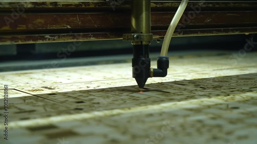 Laser engraving on plywood. An industrial laser cuts a pattern on a sheet of plywood. Modern laser processing of wood. A red laser beam passes through the tree. Close up