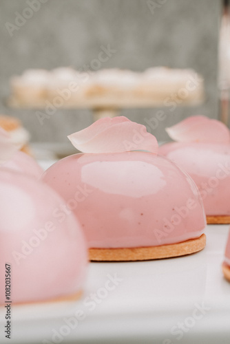 A beautiful pink dome dessert adorned with a soft rose petal, capturing elegance and sophistication. The smooth, glossy glaze and delicate presentation make this treat a perfect choice for upscale eve