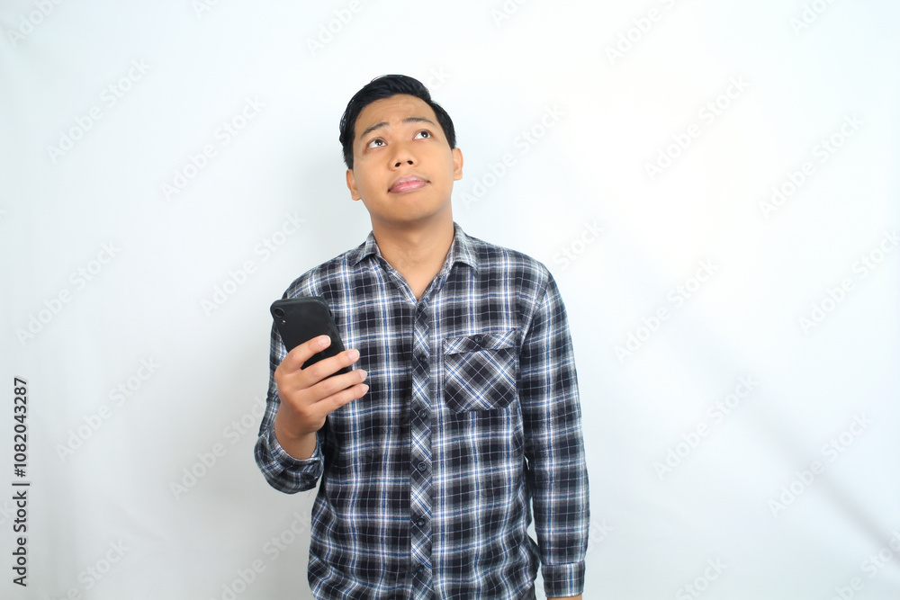 thoughtful asian man holding smartphone show confused face expression isolated on white background thoughtful asian man holding smartphone show confused face expression isolated on white background