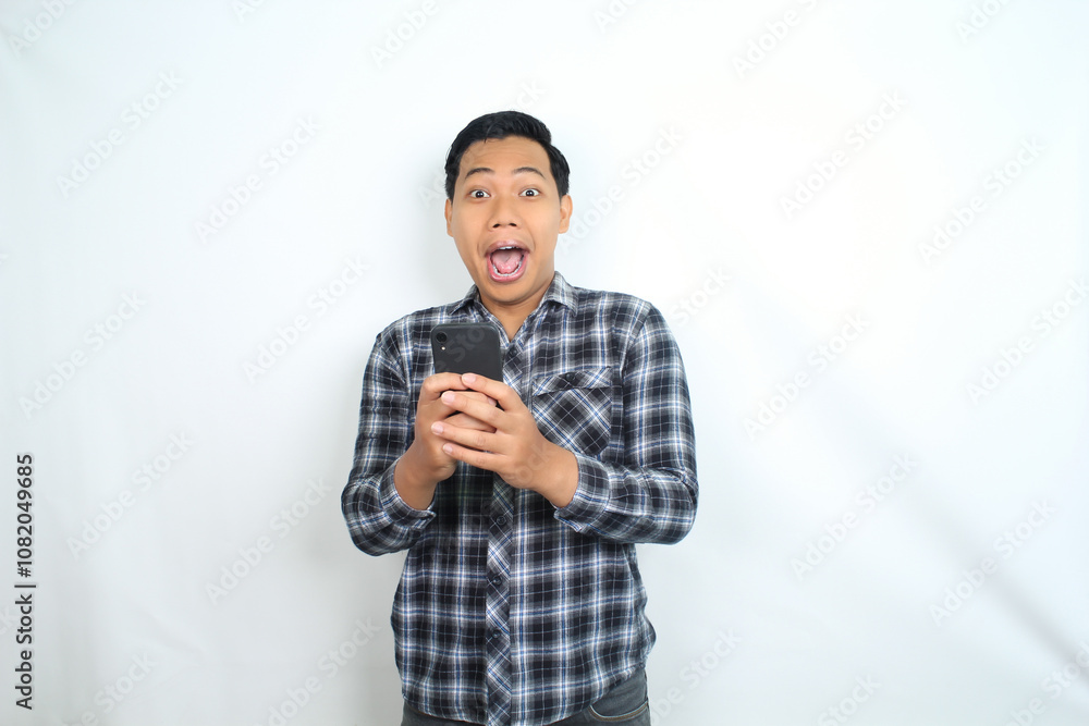 shocked asian man holding mobile phone show surprised expression with mouth open wearing casual shirt isolated on white shocked asian man holding mobile phone show surprised expression with mouth open wearing casual shirt isolated on white