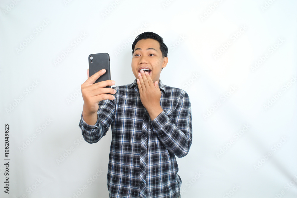 shocked asian man holding mobile phone show surprised expression with mouth open wearing casual shirt isolated on white shocked asian man holding mobile phone show surprised expression with mouth open wearing casual shirt isolated on white