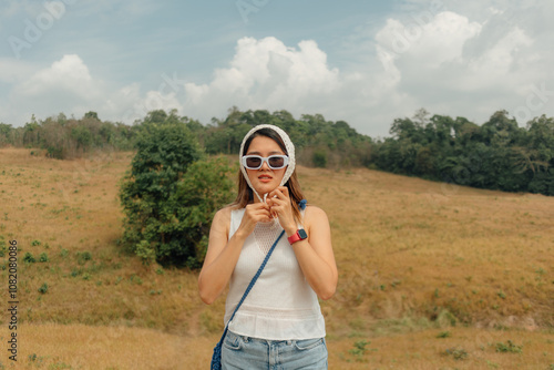 Asian woman with sun glasses tying her scarf covering her hair for outdoor trip.