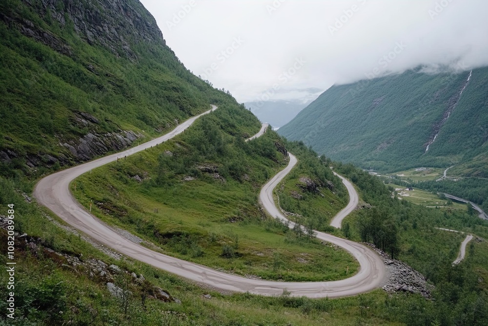Fototapeta premium Winding Mountain Road Through Lush Green Hills in Norway on a Cloudy Day With Misty Peaks