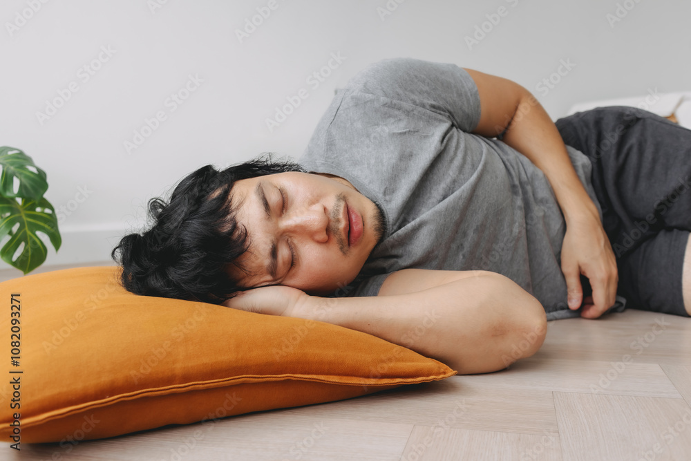 Low angle of Asian man napping on the floor take a rest in the weekend. Low angle of Asian man napping on the floor take a rest in the weekend.