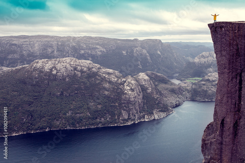 girl raised her hands up standing on the famous Preikestolen Pulpit Rock