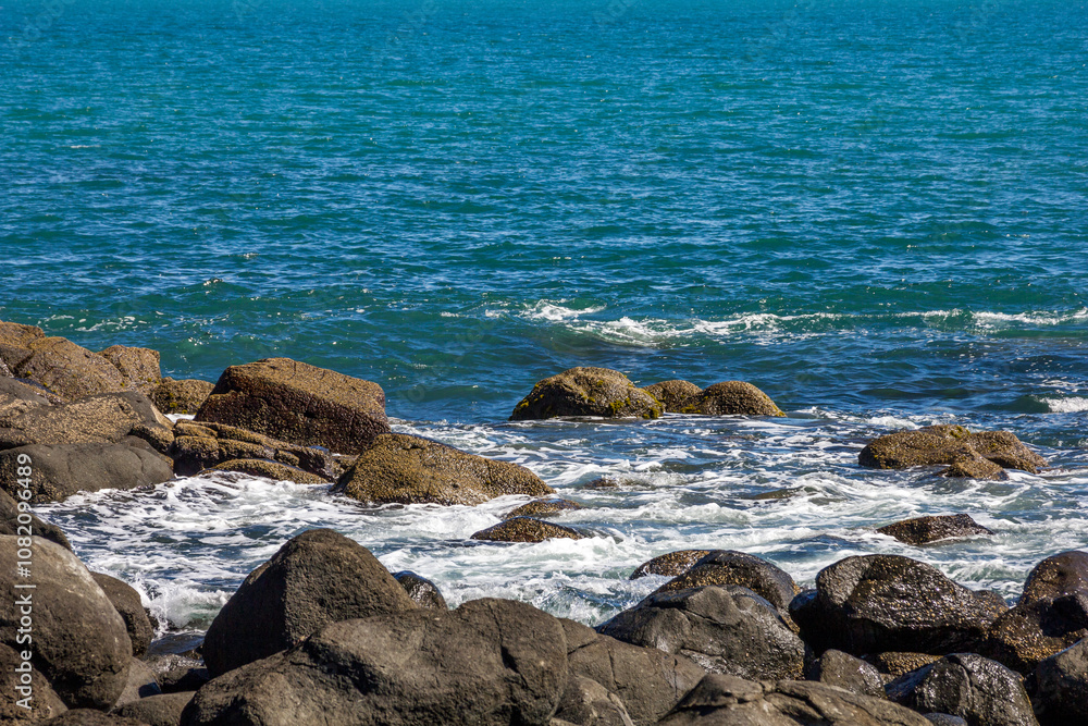 Large waves crash into coastal rocks. Dramatic sea shore background. Raglan, New Zealand Large waves crash into coastal rocks. Dramatic sea shore background. Raglan, New Zealand