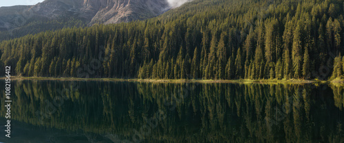 Lake Engolasters - A reflective lake surrounded by dense pine forests and mountains. photo