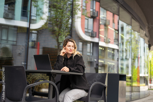 Businesswoman working with laptop in outdoor cafe. Corporate blog