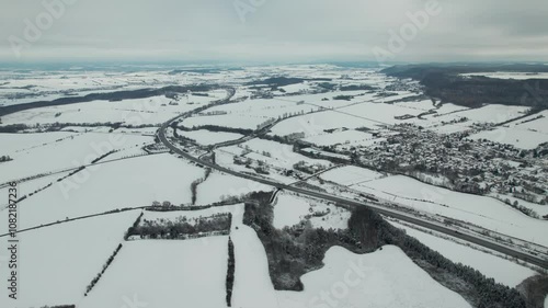 Flying over a highway and a small village covered in snow in Germany. High quality 4k footage