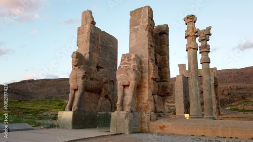 Camera panning across massive statues at persepolis, iran, showcases the stunning architecture during a vibrant sundown