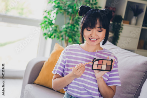 Wall Mural Photo of shiny cute girl dressed purple striped t-shirt applying cosmetics indoo