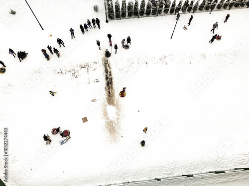 A winter gathering of people enjoying snow activities in a park with sledding, snowboarding, and laughter amidst a snowy landscape photo