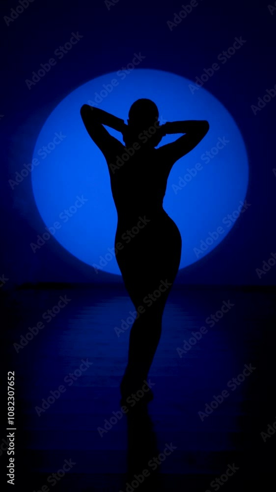 Silhouette of a woman dancing in blue neon light.Woman dancing dance in a blue light circle.Dance and movement concept.Vertical video Silhouette of a woman dancing in blue neon light.Woman dancing dance in a blue light circle.Dance and movement concept.Vertical video