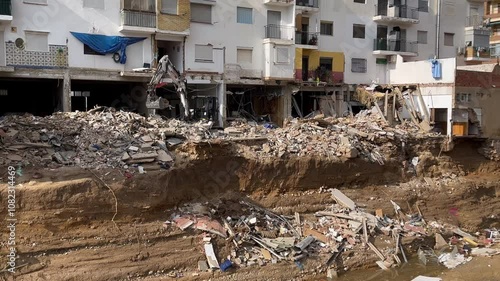 Excavator clearing rubble after controlled partial demolition of buildings damaged by the flood caused by the intense rains of the Dana over the Valencian Community