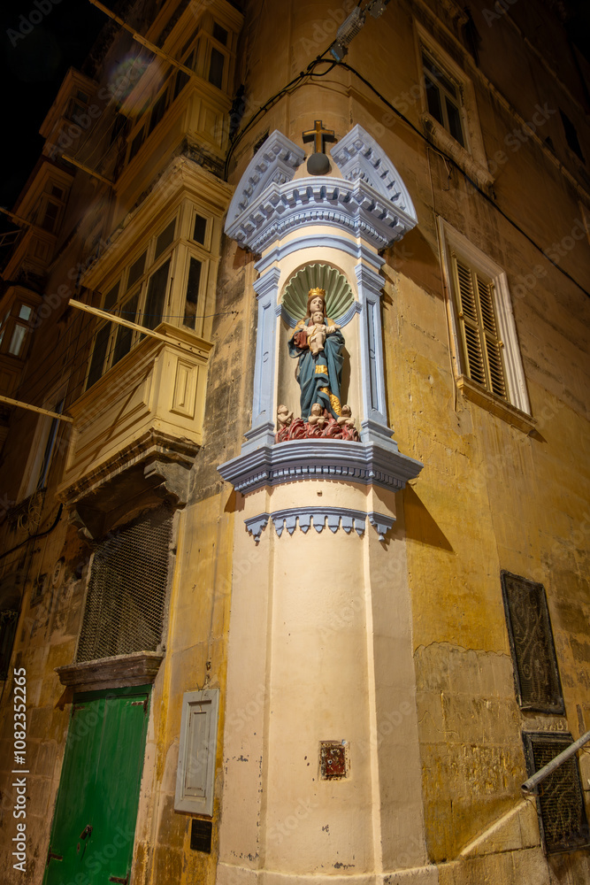 Obraz premium Valletta, Malta A Madonna statue on the side of a building at night in old Valletta.