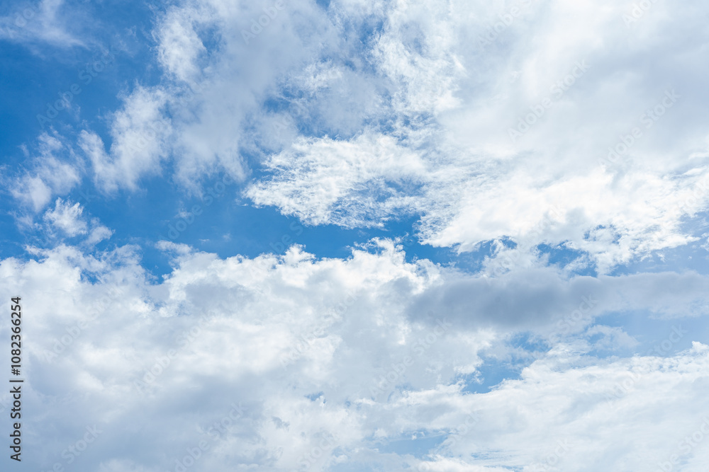 Fluffy white cumulus clouds drift across a bright blue summer sky Fluffy white cumulus clouds drift across a bright blue summer sky