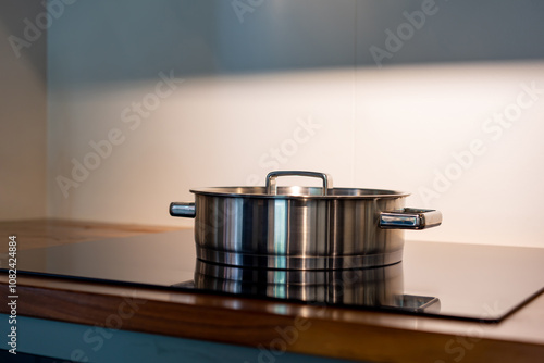 stainless steel pot on electronic modern flat stove in low light on counter kitchen room