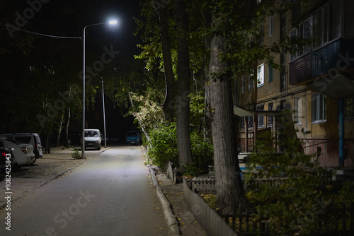 Night city landscape, village houses, road, sky and trees on a summer evening